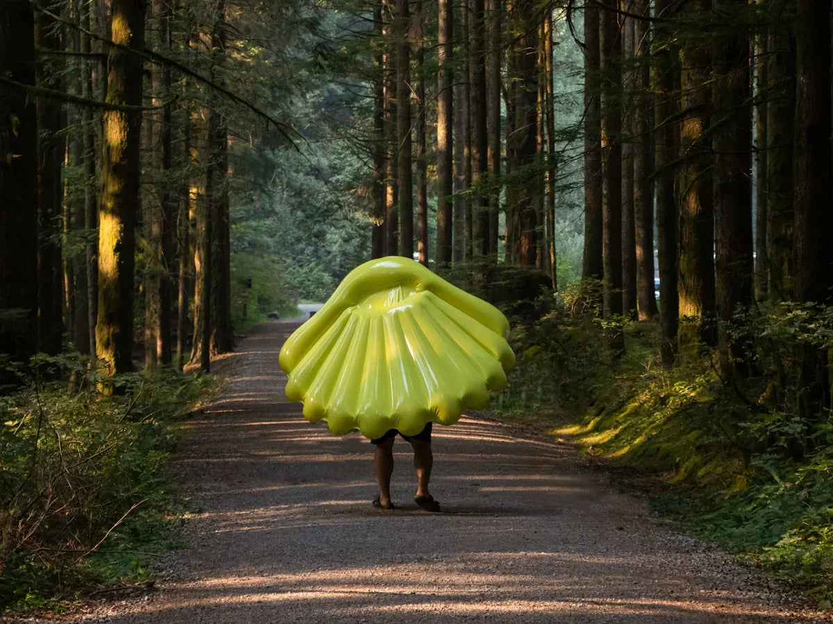 person using green sea shell hat walking near tall trees