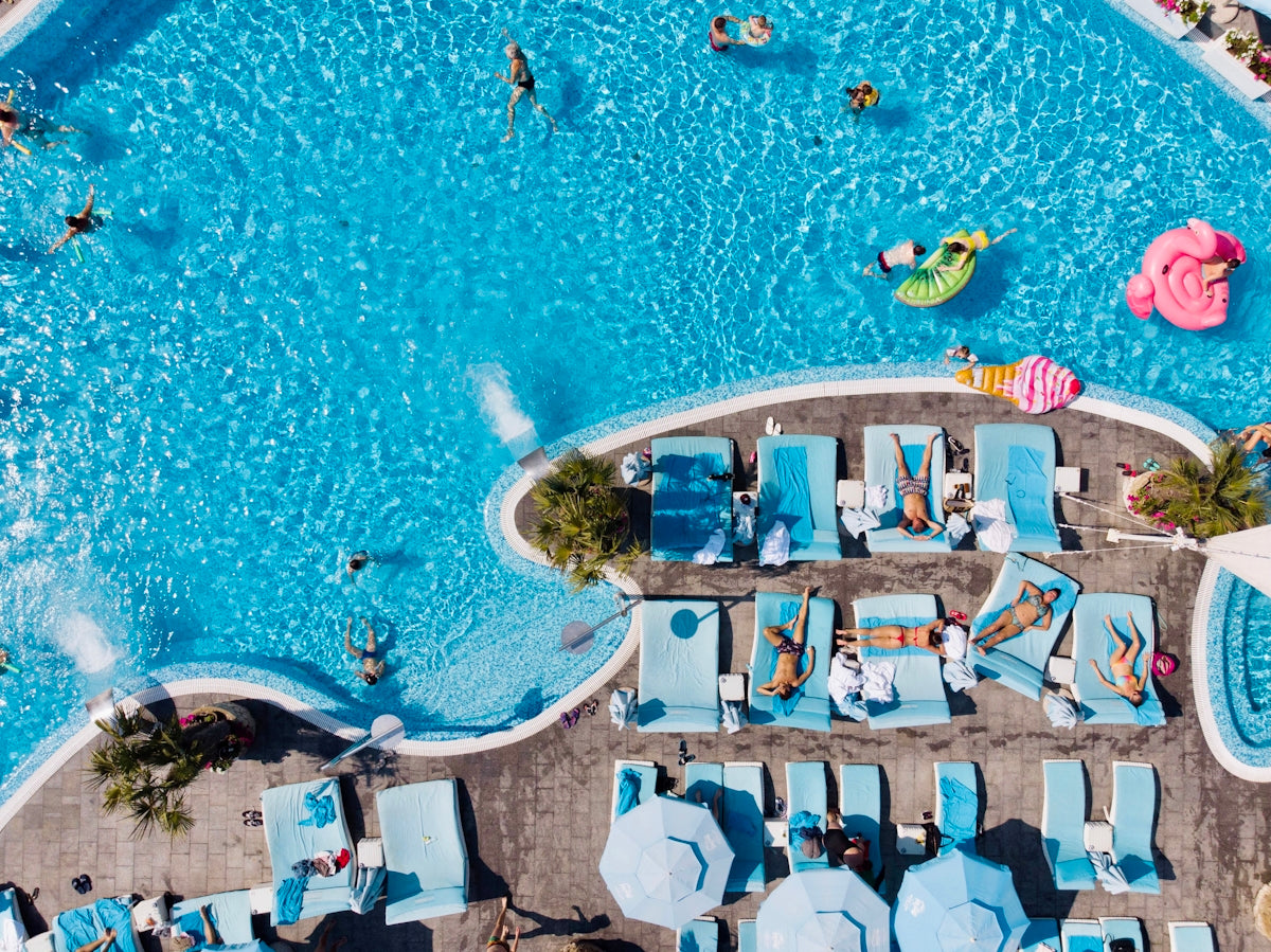 an overhead view of a pool with lounge chairs and inflatable toys