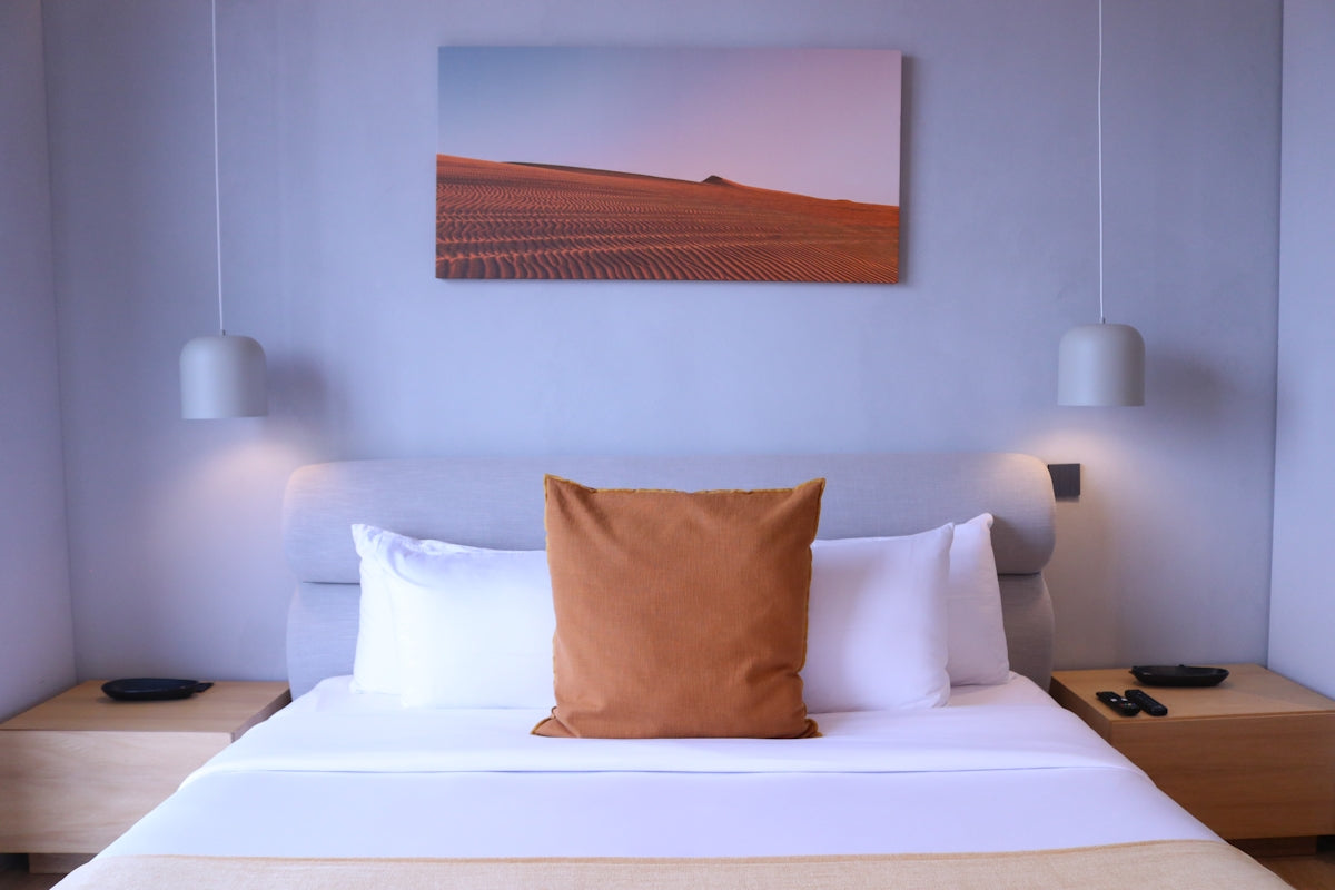 a bed with a white bed spread and a painting on the wall