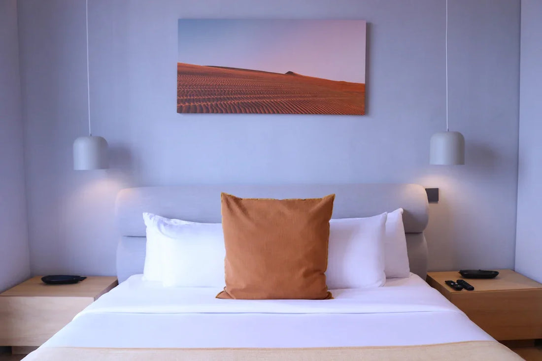 a bed with a white bed spread and a painting on the wall