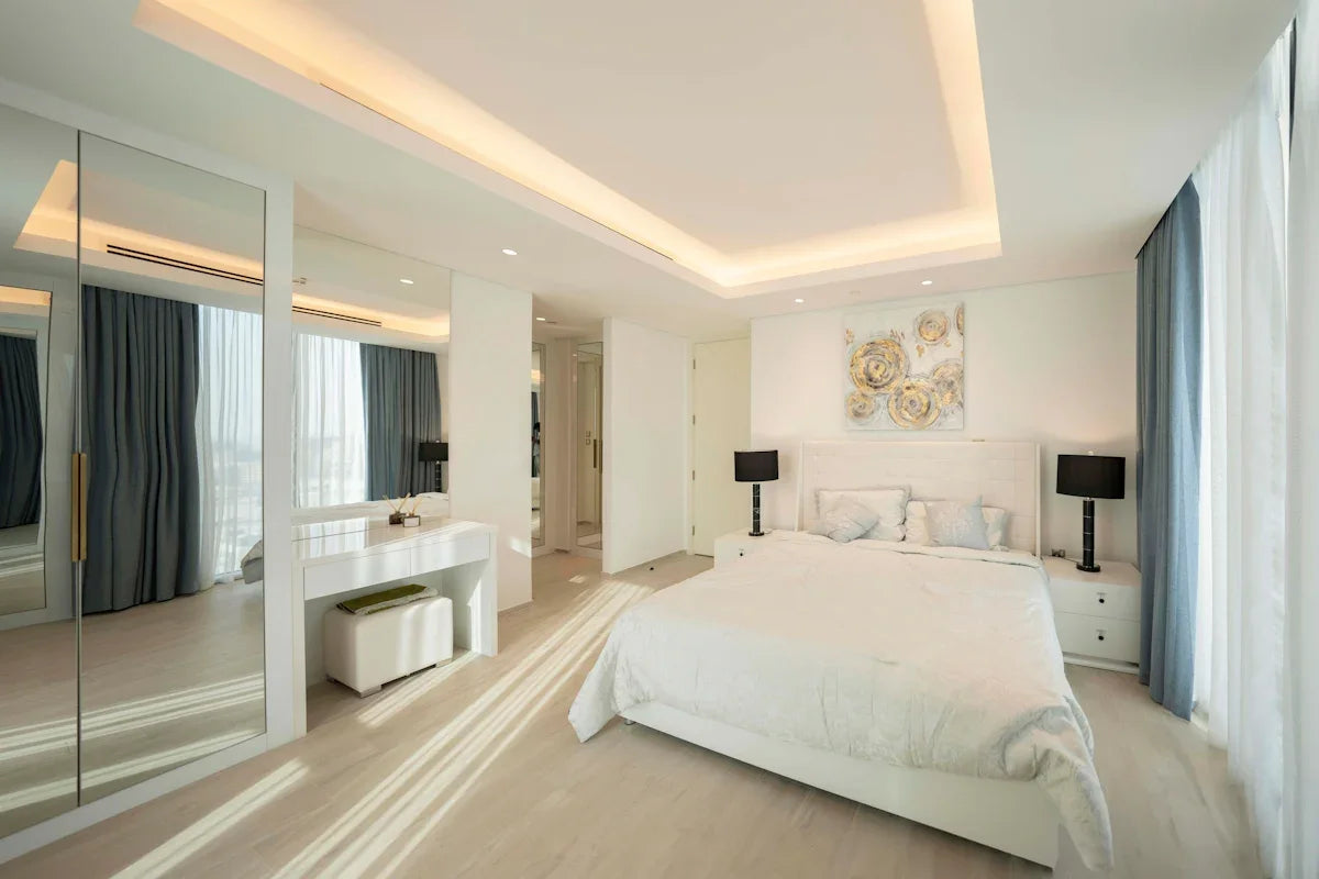 A bedroom with a large white bed sitting next to a window