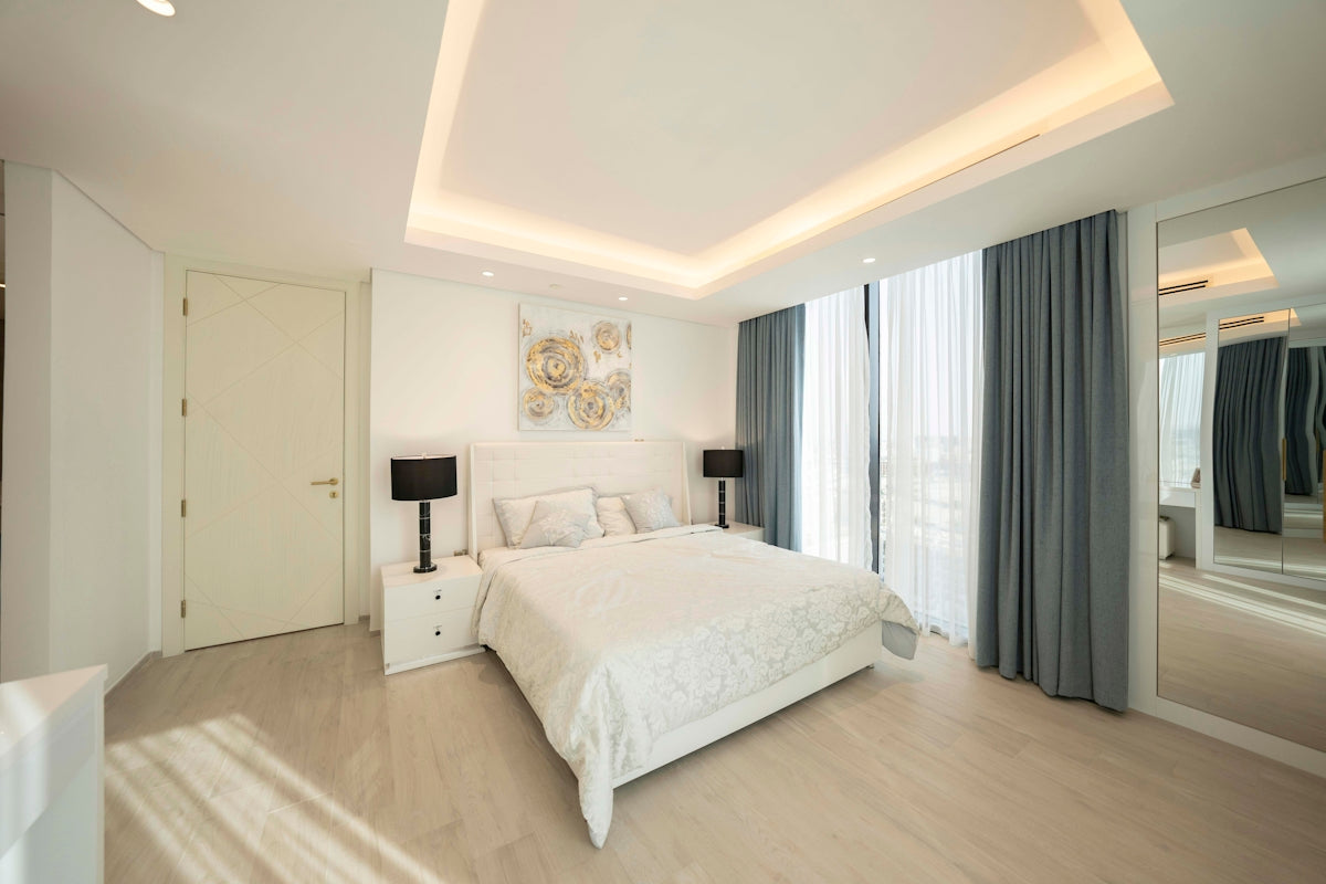 A bedroom with a large white bed sitting next to a window