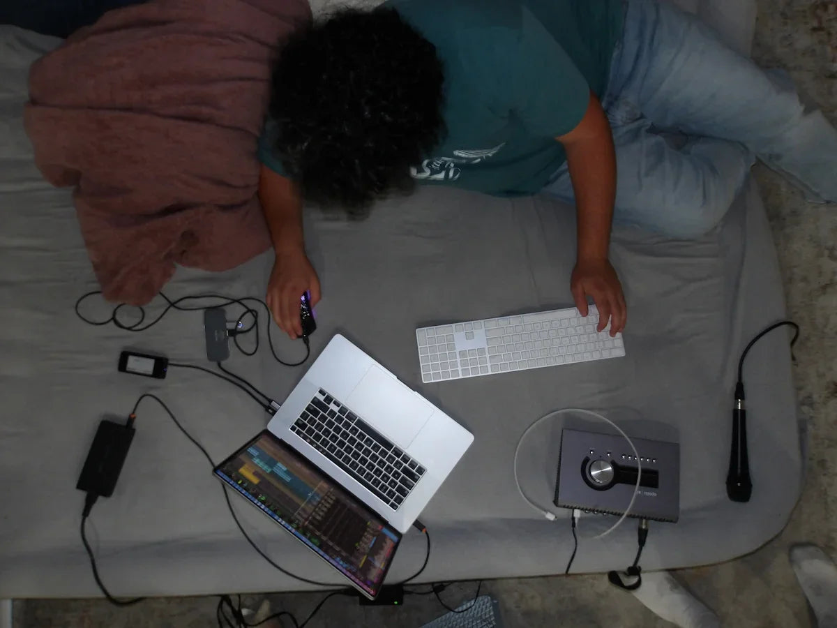 A person laying on a bed with a laptop
