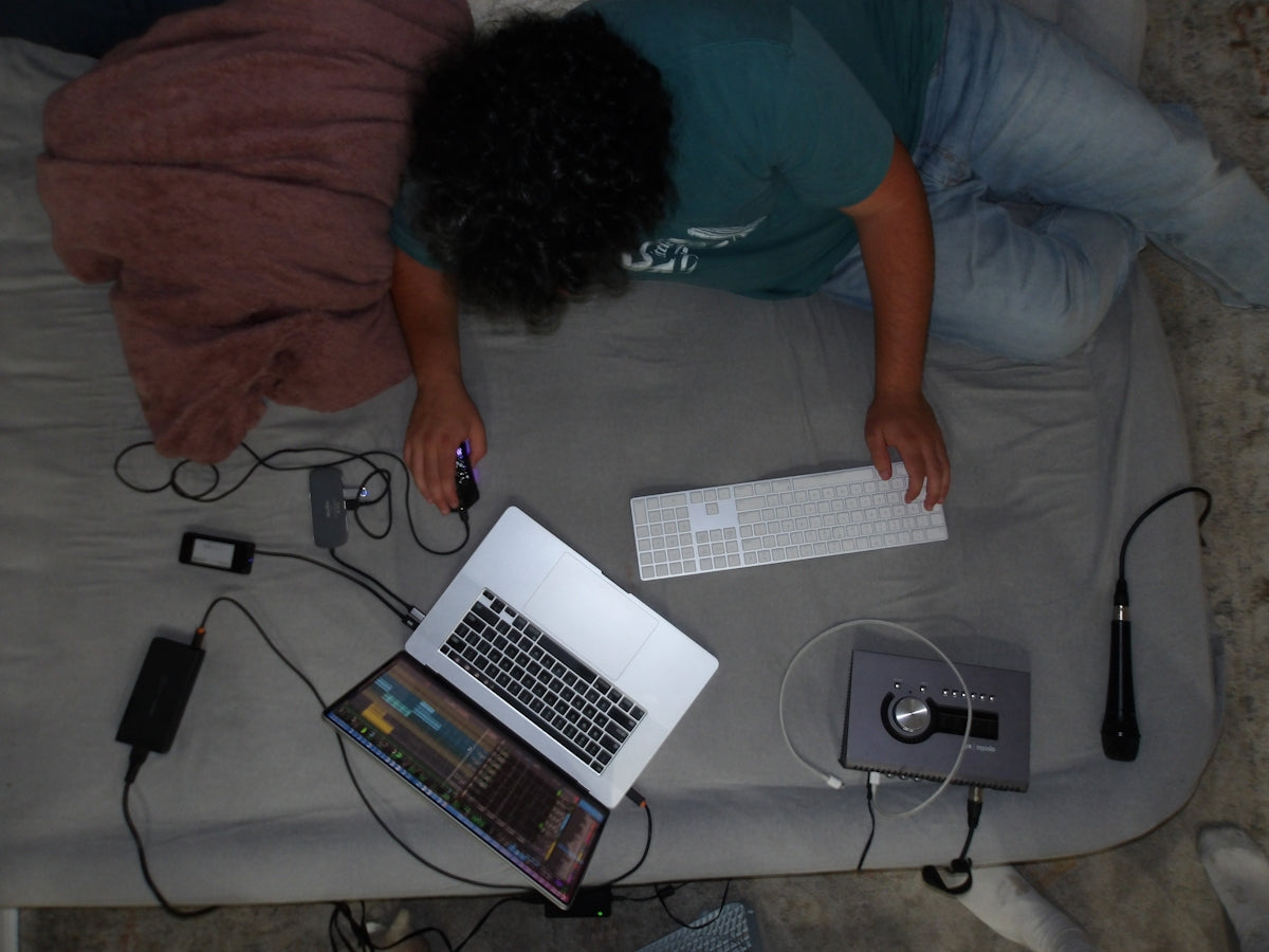 A person laying on a bed with a laptop