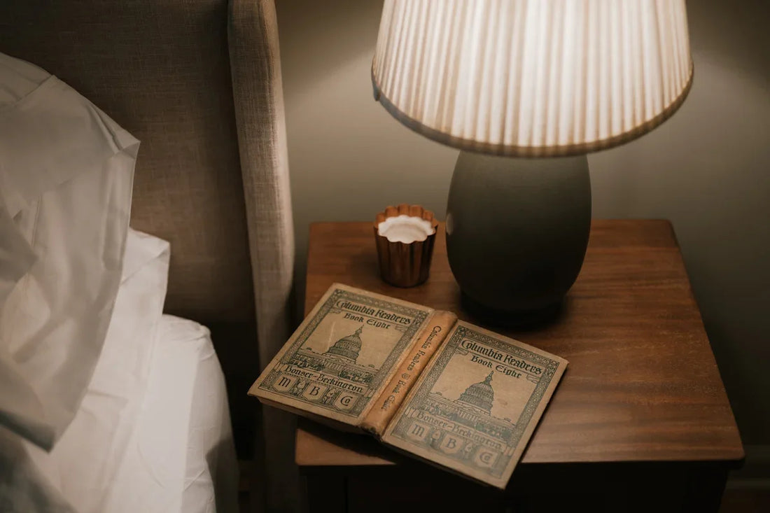 Open book on bedside table with lamp