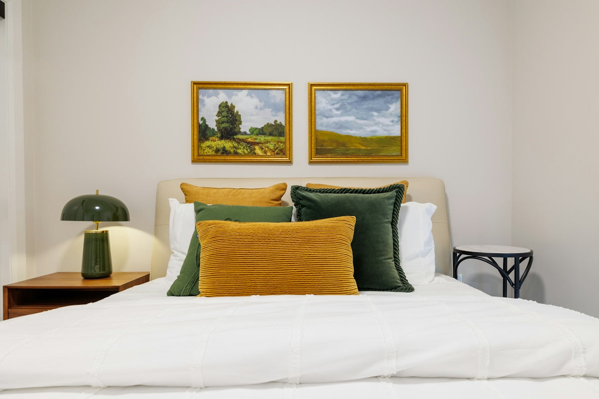 Bedroom with landscape paintings and green lamp