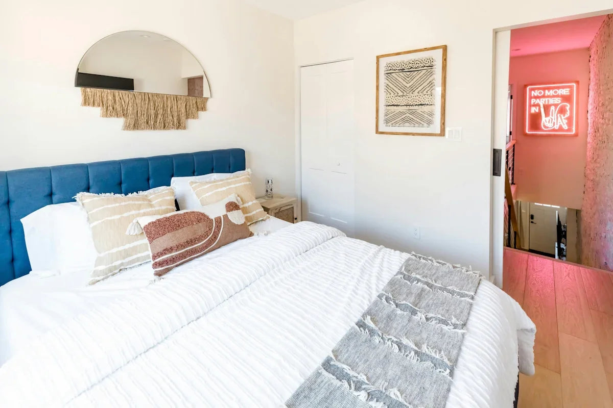 A cozy bedroom with a blue headboard and decorative mirror.