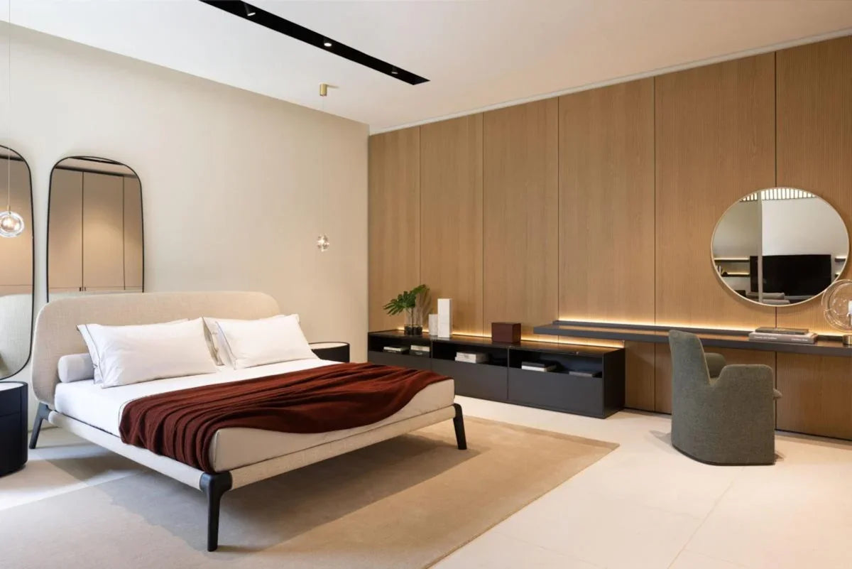 Modern bedroom with a bed, desk, and mirrors.