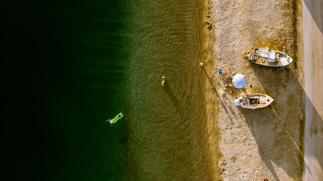 Aerial view of people and boats on a sunny beach.