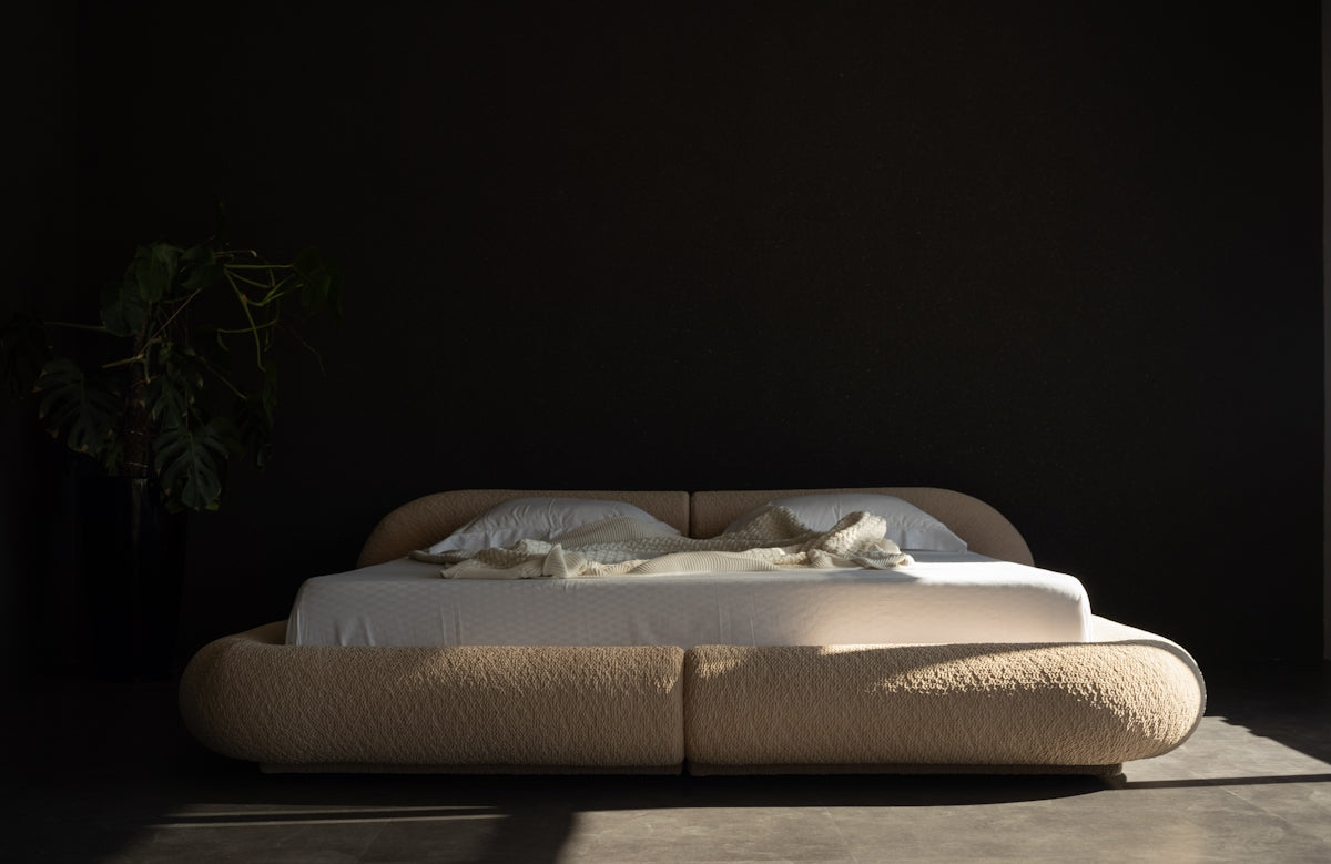 A modern bed with plush upholstery and white linens.
