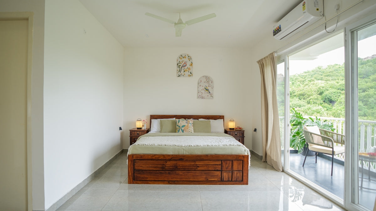 Bedroom with a large bed and balcony overlooking hills