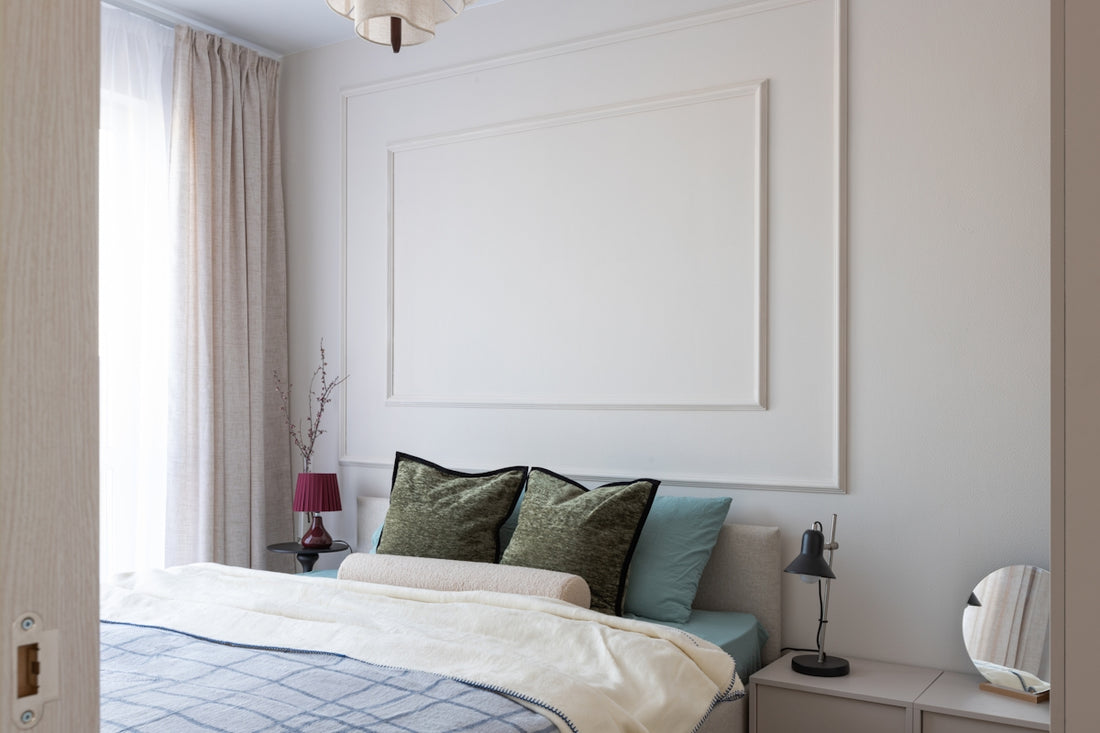 A minimalist bedroom with a large ornate frame above bed.
