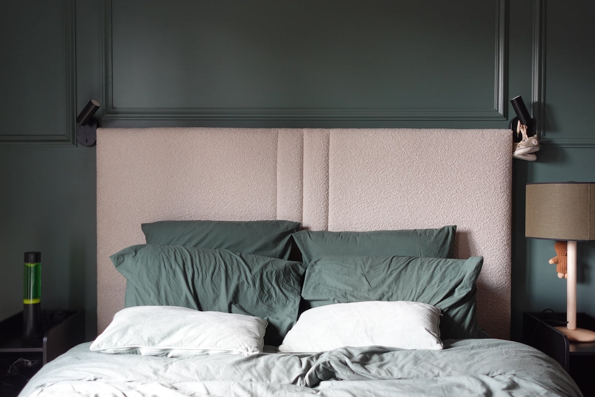 A bed with pillows and a lamp on a nightstand.