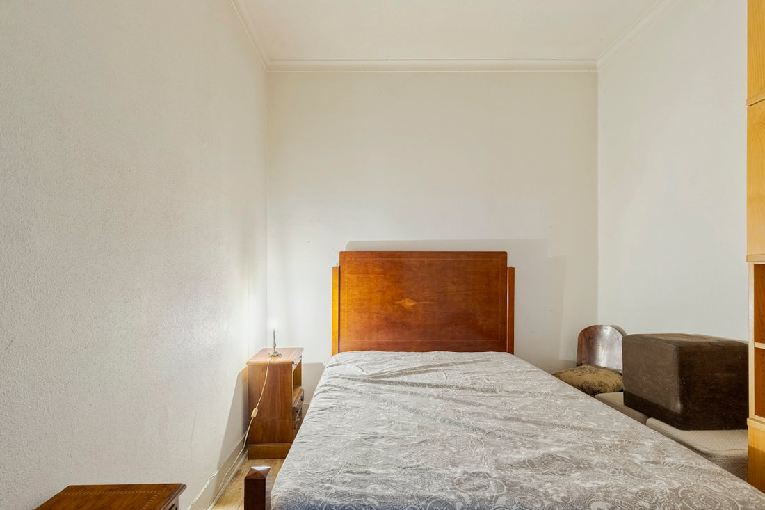 A simple bedroom with a single bed and wooden furniture