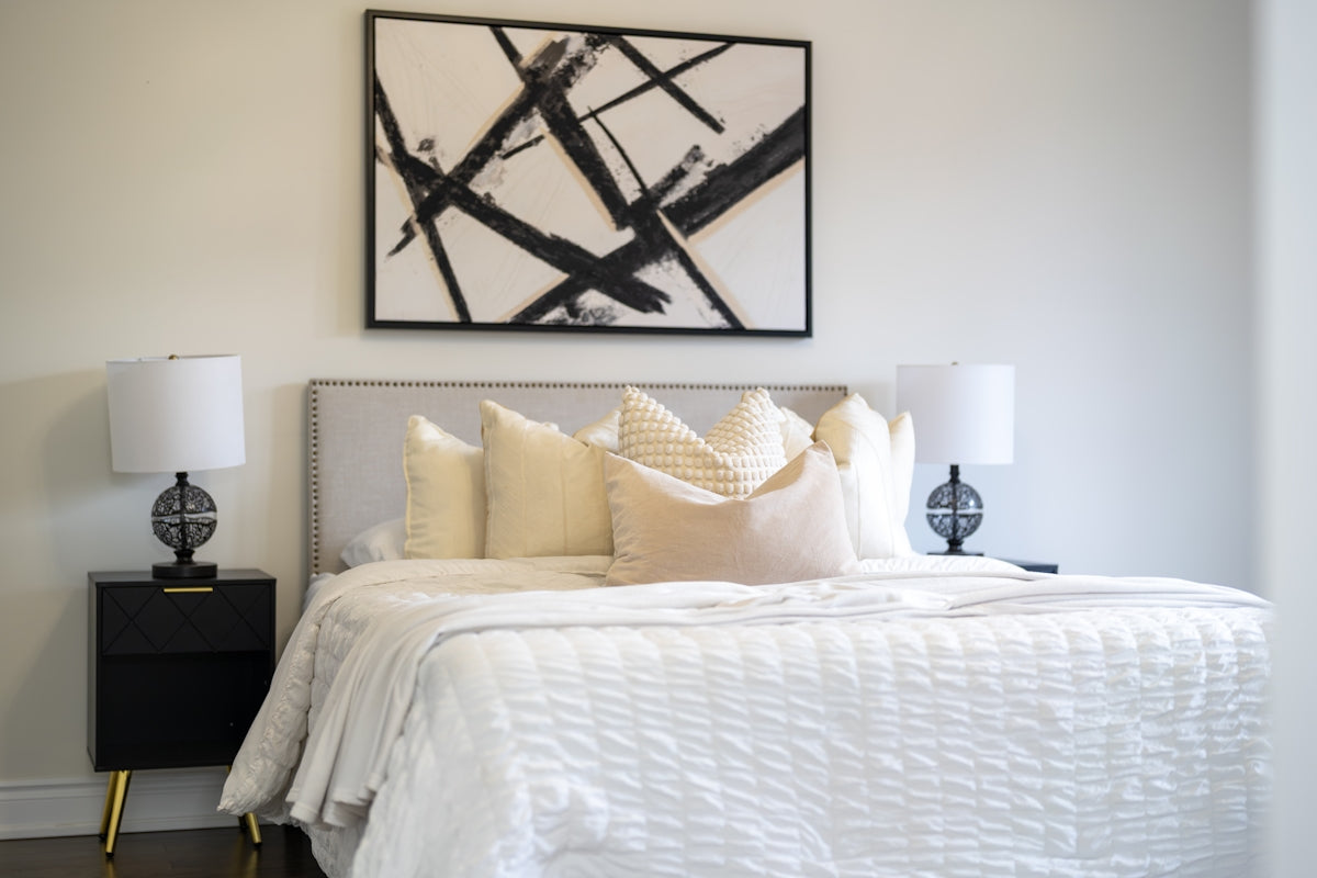 A modern bedroom with a king-size bed and abstract art.