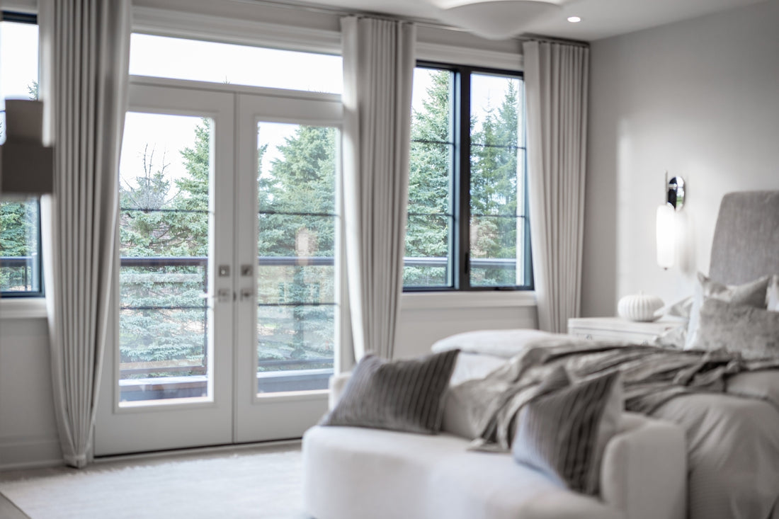 Modern bedroom with large windows overlooking green trees.