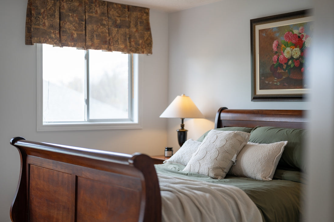 Bedroom with sleigh bed, pillows, and painting.