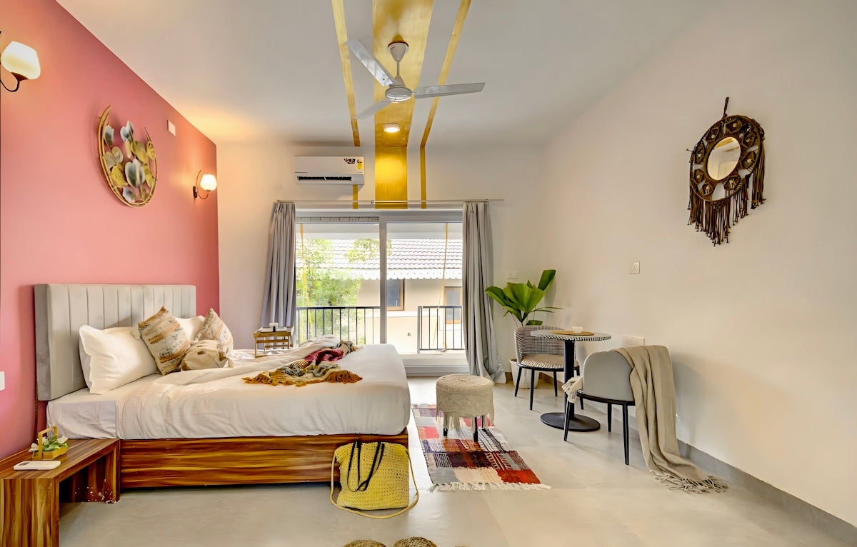 Cozy studio apartment with a bed, pink wall, and balcony.