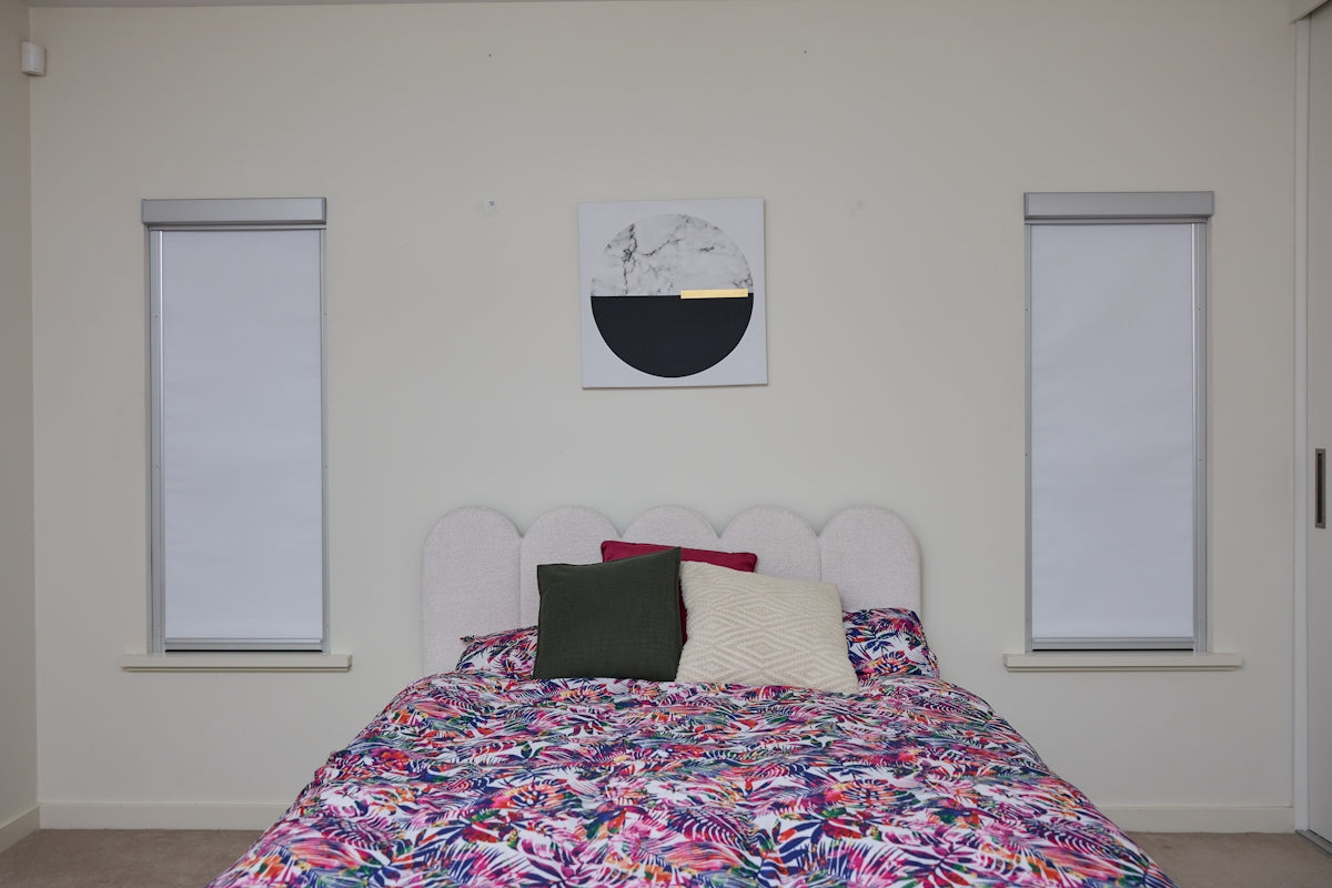 A bedroom with a bed, floral duvet, and abstract art.
