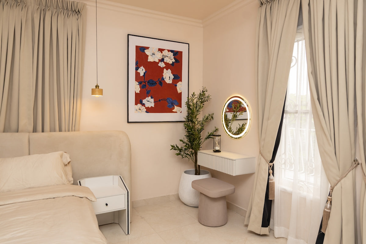 Elegant bedroom interior with bed, artwork, and lighted vanity.