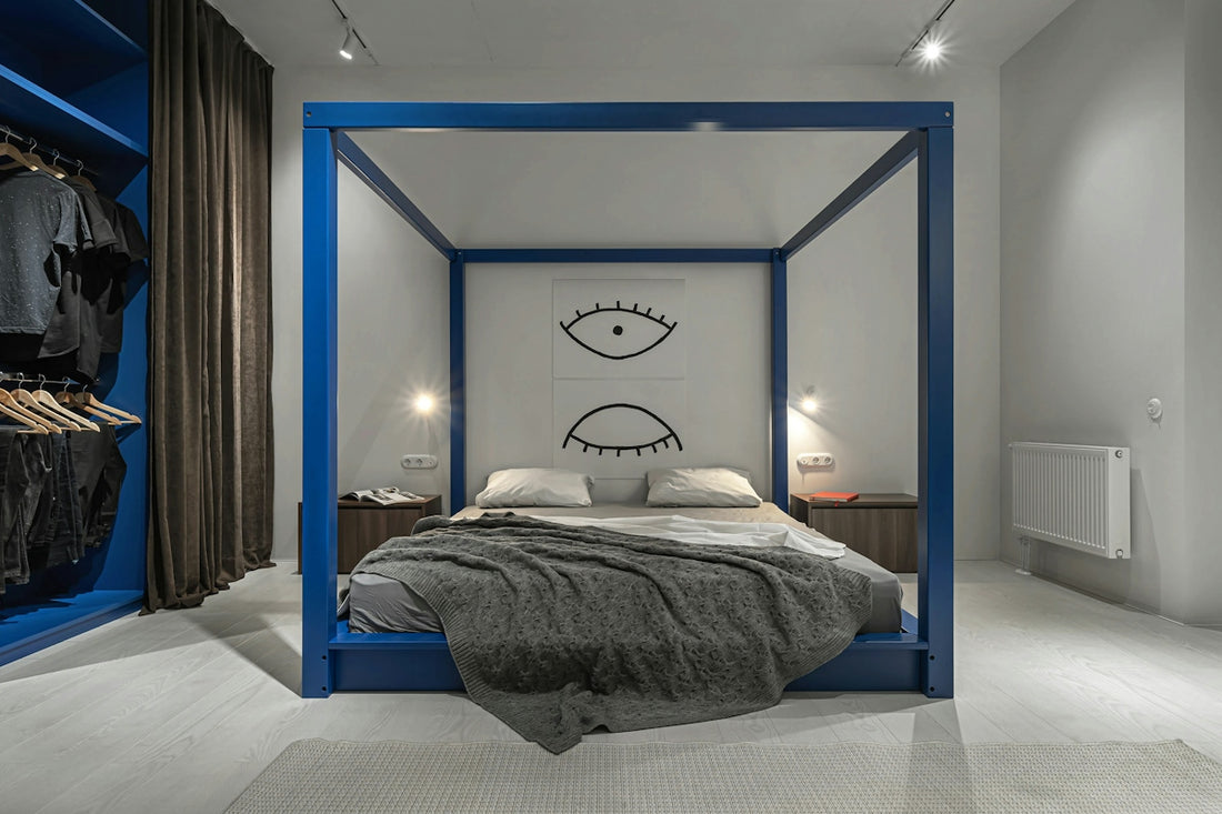 A blue canopy bed with a grey knit blanket in a modern bedroom
