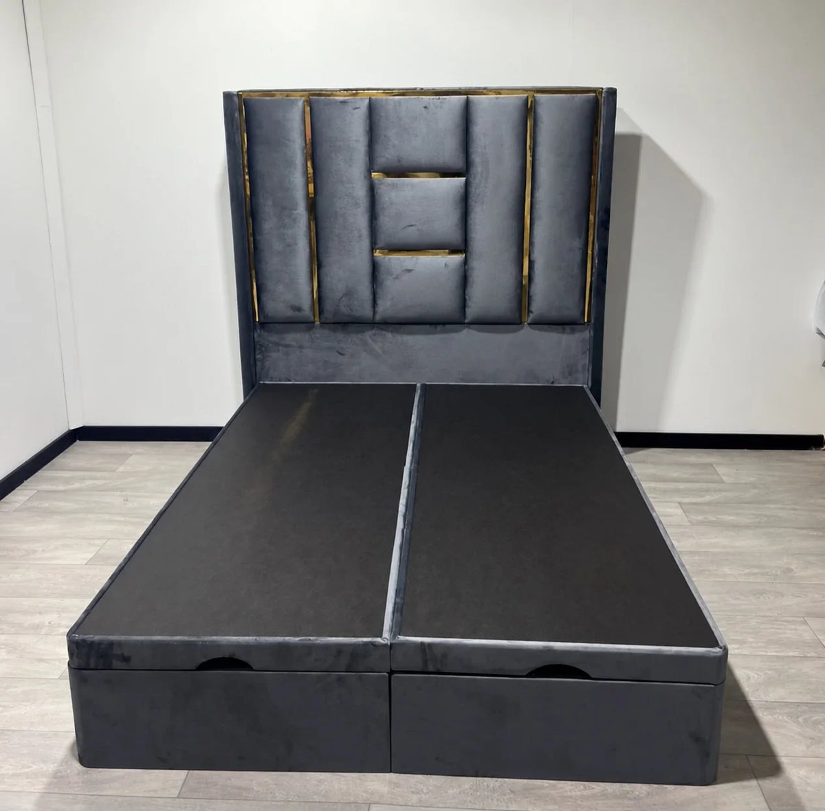 Front view of the Luxe Panel Ottoman Bed in grey upholstery with gold headboard detailing